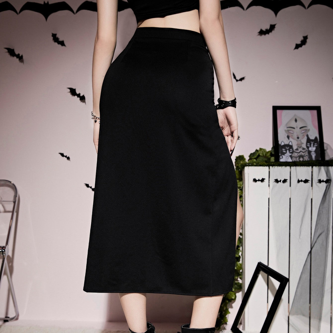 A woman in a Maramalive™ Gothic Style Lacing Half Skirt with thigh splits posing in front of a wall with bats.