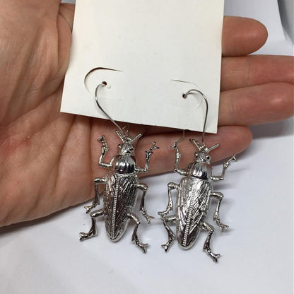 A pair of Gothic Alloy Cockroach Insect Earrings Europe And America by Maramalive™ in a person's hand.