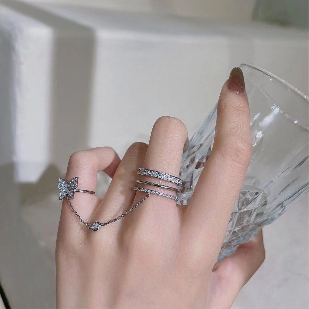 A woman's hand holding a glass with the Maramalive™ Net Red Butterfly Tassel Finger Ring Special-interest Design on it.