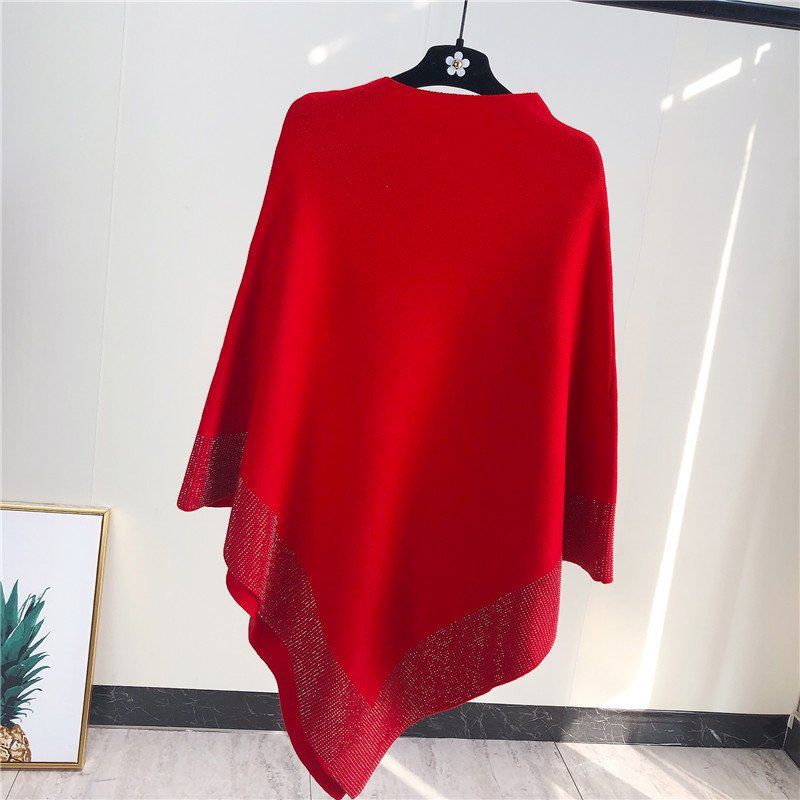 A red knitted Outer Bat Sweater With Diamond Studded Black Sweater by Maramalive™, perfect for a simple commuting style, is displayed on a hanger against a light-colored background, with a picture of a pineapple partially visible in the lower-left corner.