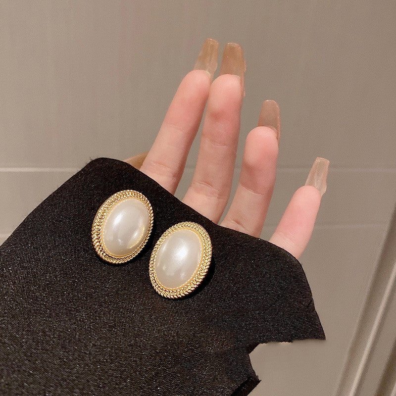 A hand holding a pair of Maramalive™ French Baroque Pearl Earrings.