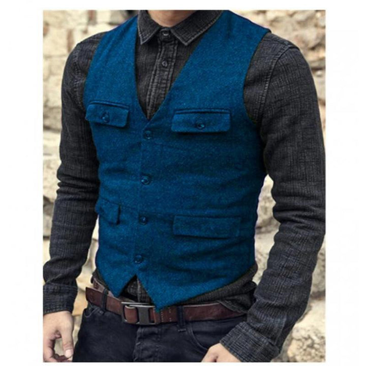 A person wearing a Maramalive™ European And American Men's Vest Casual Solid Color Herringbone Vest over a dark shirt, with a brown belt, stands against a stone background, embodying British style in their cotton blend attire.