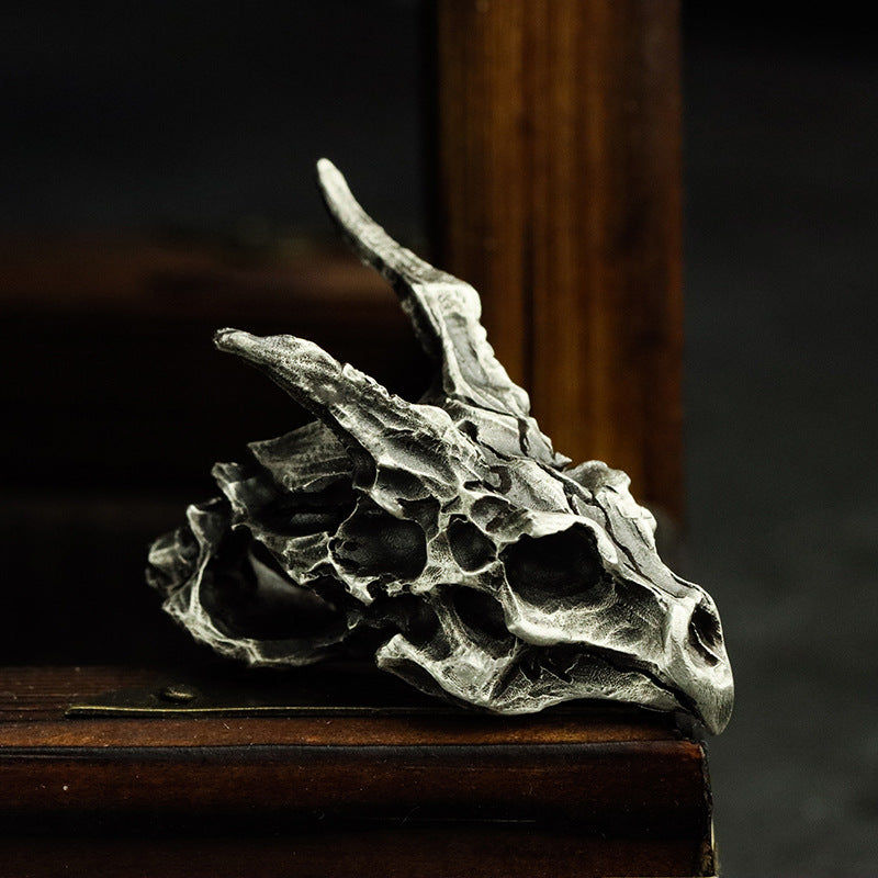 A Sterling Silver Brass Demon Dragon Pendant by Maramalive™ sitting on a piece of wood.
