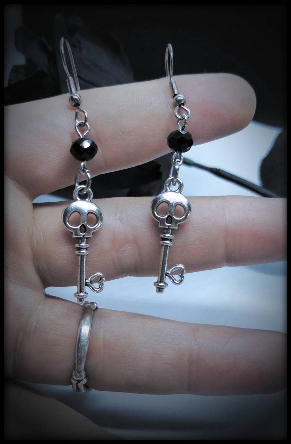 A pair of CJ Fashion Gothic Skull Earrings Jewelry Gift with a key on them.