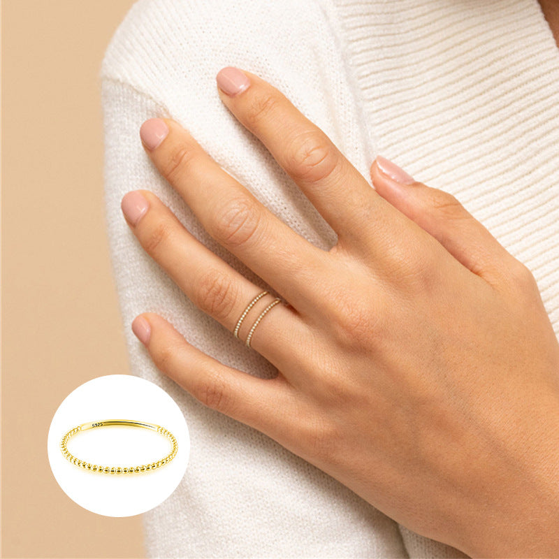 A woman wearing a white sweater with a Maramalive™ Sterling Silver Line Ball Ring on her hand.