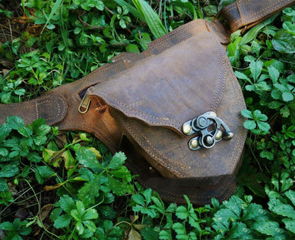 A brown leather Medieval Steampunk Vintage Heart Belt Satchel by Maramalive™ laying in the grass.