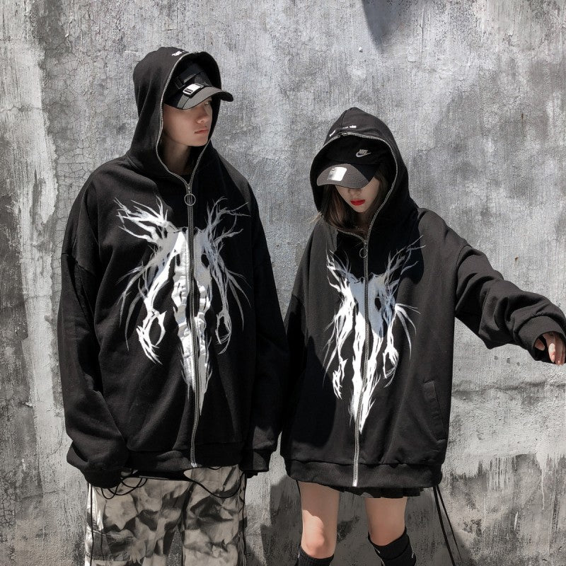 Two individuals wearing black, Maramalive™ FallWinter College BF Wind Hooded Cardigan Sweatshirt National Tide Printed Loose Sports Casual Hoodies with white, tree-like designs stand against a concrete wall. Both have their hoods up and are also wearing black caps and casual clothing.