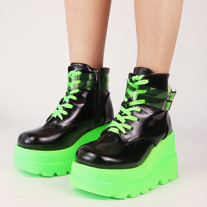 A woman wearing Maramalive™ Dark Gothic Wedge Platform Ankle Boots in a bold black and green color combination, showcasing a unique design.