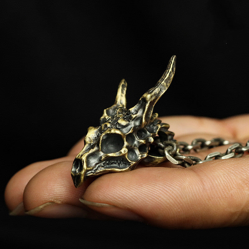 A Sterling Silver Brass Demon Dragon Pendant by Maramalive™ sitting on a piece of wood.