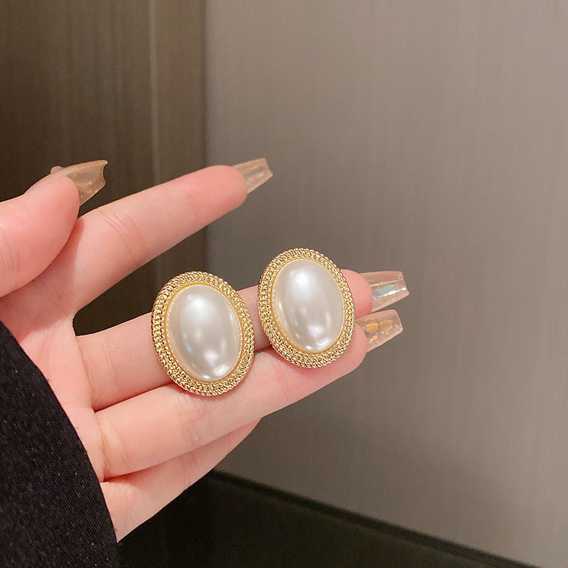 A hand holding a pair of Maramalive™ French Baroque Pearl Earrings.