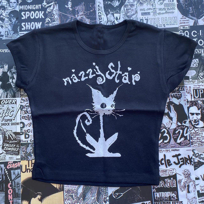 A Gothic Street T-shirt Women's Printed Black Top with a stylized cat illustration and the text "Mazzy Star" printed on it, laid flat on a surface covered with various posters, exudes a Gothic style charm. This top is by Maramalive™.