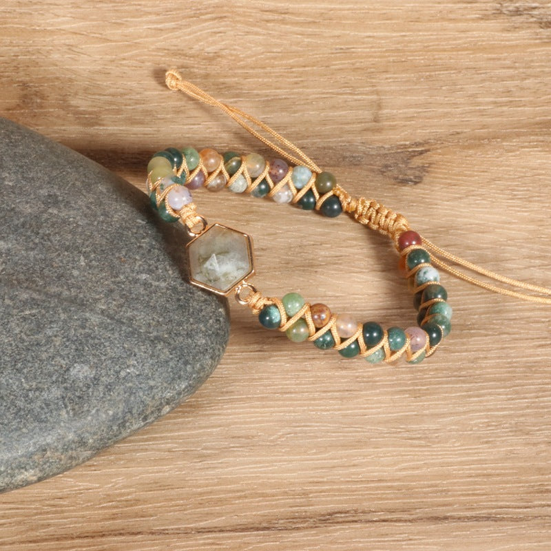 A Gorgeous Agate Hexagonal Charm Braided Bracelet with green stone and gold beads on top of a rock by Maramalive™.