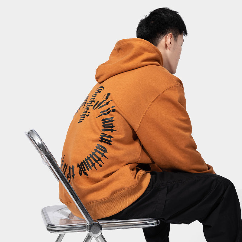 A person wearing a Maramalive™ European Hip Hop Gothic Sweater Men's Hoodie with an orange hoodie featuring black text on the back sits on a transparent chair facing away from the camera.