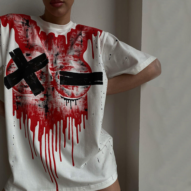 A person wears a Maramalive™ Chic Oversized Short Sleeve Tee for Women with bold red paint drips and black tape Xs over the chest area, standing near a corner of a room.