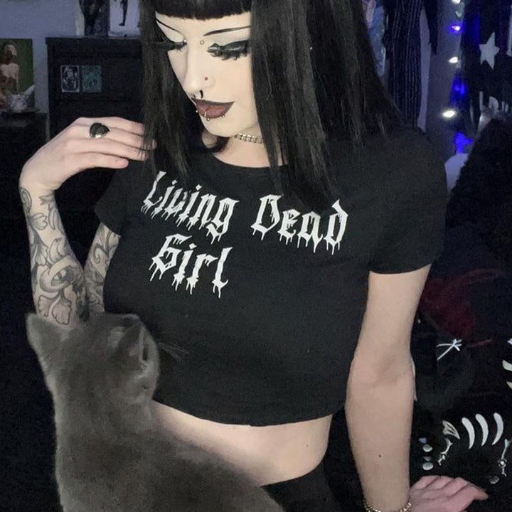 A person with dark hair and tattoos is wearing a "Gothic Style Printed Top Short Sleeve" t-shirt by Maramalive™ made from black modal short sleeve polyester fiber. They are looking down at a gray cat.