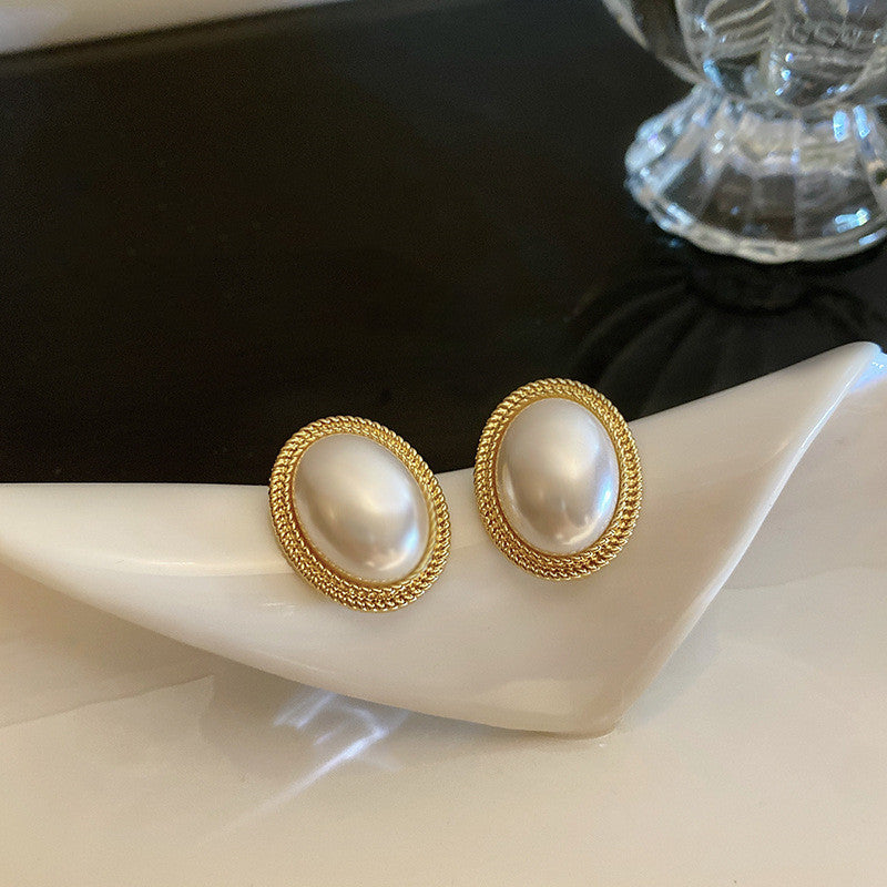 A hand holding a pair of Maramalive™ French Baroque Pearl Earrings.