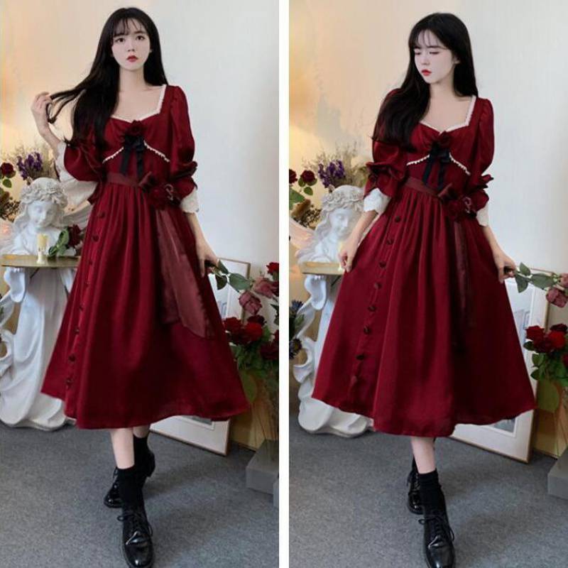 A woman in a Maramalive™ Velveteen Gothic Red-Rose Dress: Vintage Wine-Red Frock standing in front of flowers.