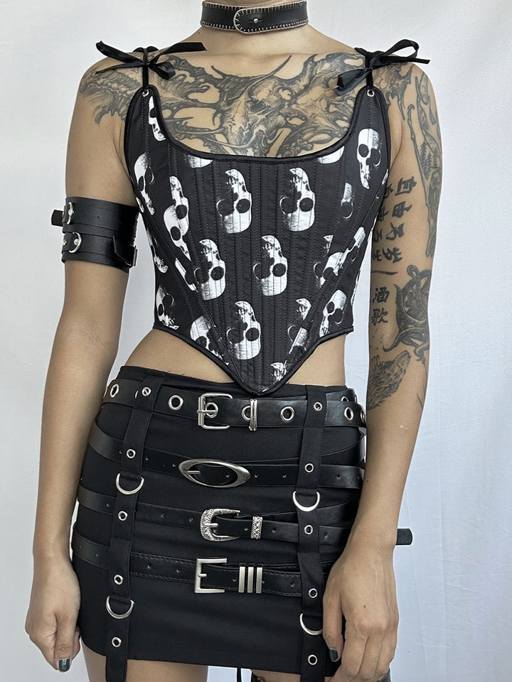 Person wearing a black skull-print *Exclusive Dark Gothic Punk Corset tie Designs Unveiled* by *Maramalive™* vest and a black leather belt skirt with multiple straps and buckles, accessorized with a choker and armband. Their arms are covered in tattoos, exuding a strong gothic punk aesthetic.