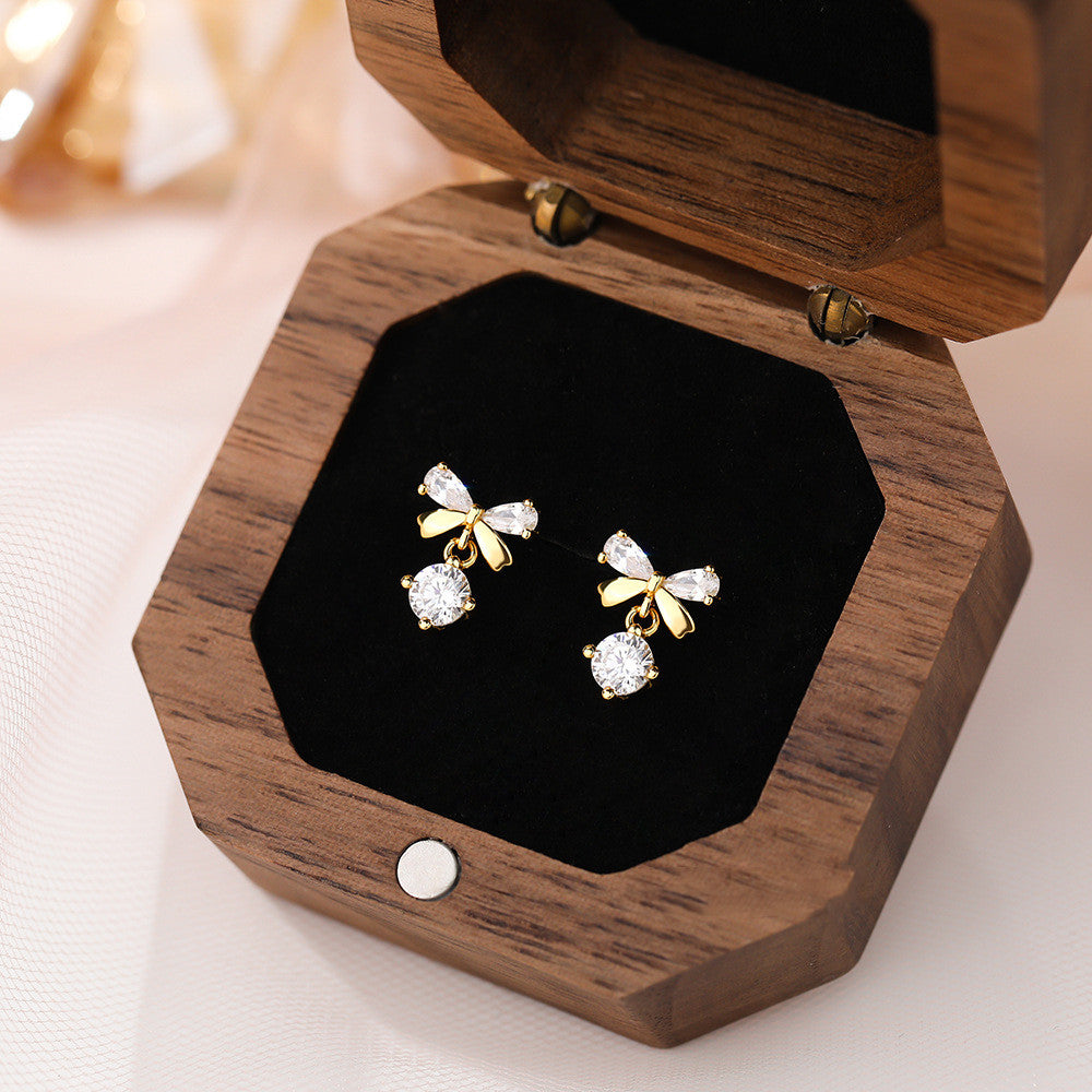 A woman wearing a white shirt and a pair of Maramalive™ Women's Graceful And Fashionable Pure Silver Zircon Bow Stud Earrings.