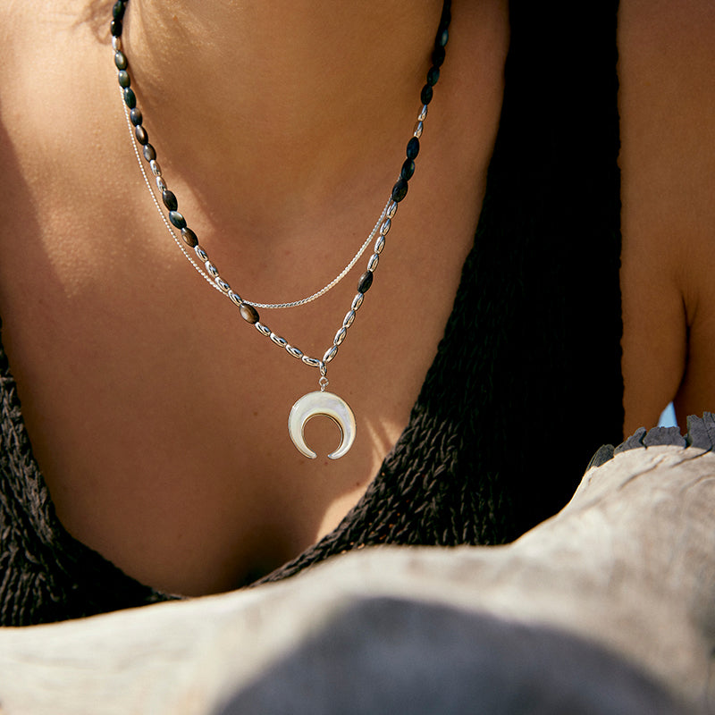 A woman wearing the Double Layer Moon Fritillary Pendant by Maramalive™ on the beach.