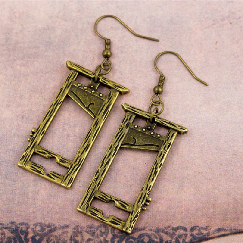 A pair of Guillotine Gothic Earrings Halloween Vintage Nature by Maramalive™ on a person's hand.