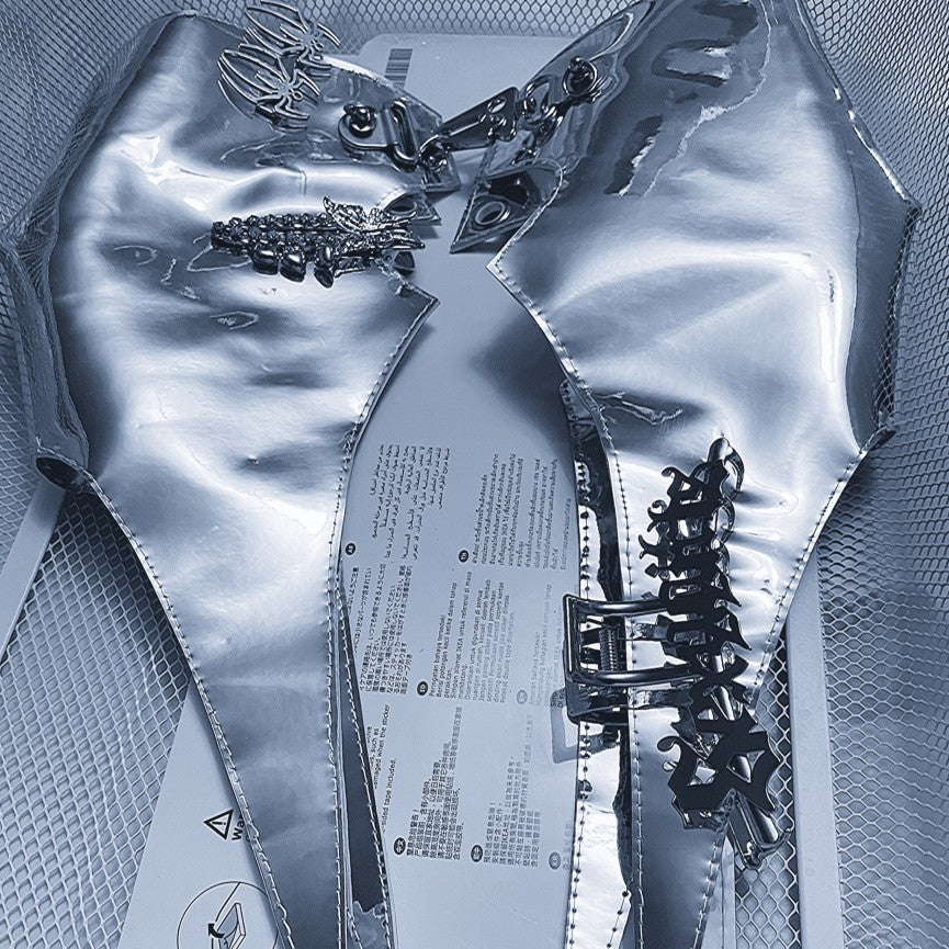 A silver metallic garment featuring sharp, pointed designs adorned with electroplated jewelry and various metal accessories and buckles, displayed on a mesh surface: the Punk Futuristic Silver Metallic Performance Suit by Maramalive™.