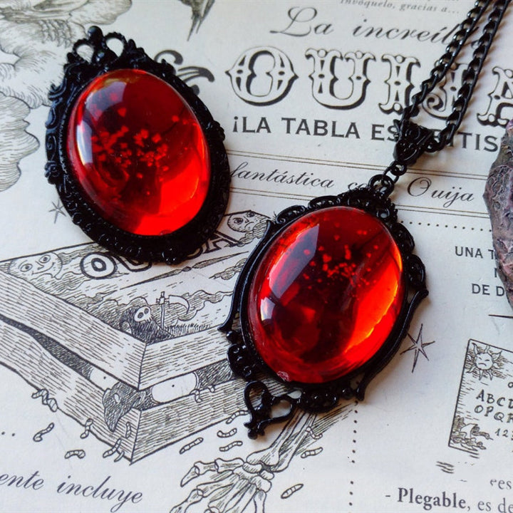 Two Witching Hour necklaces with red and purple stones arranged on an old book for a Halloween vibe by Maramalive™.