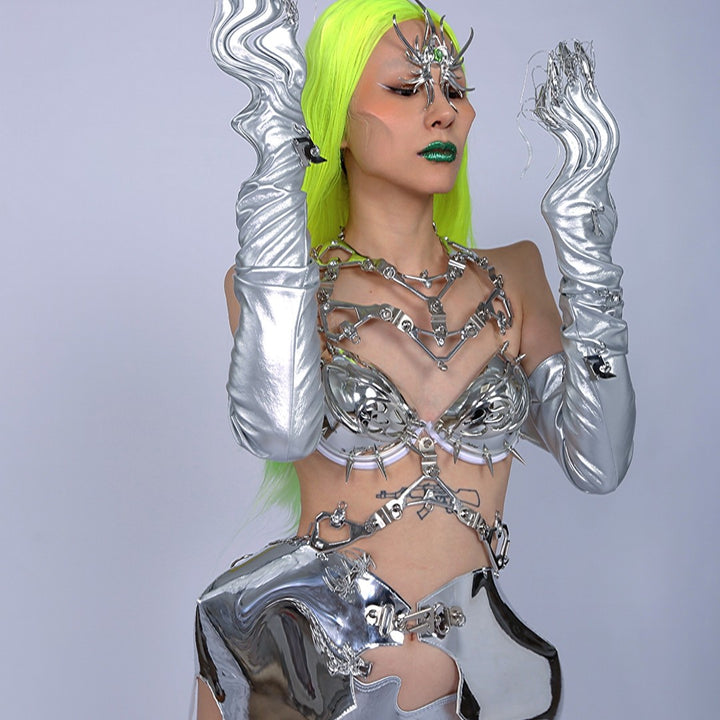 A person with long, neon green hair wears a Punk Futuristic Silver Metallic Performance Suit by Maramalive™ with chrome accessories and robotic gloves, complemented by electroplated jewelry and standing against a plain background.