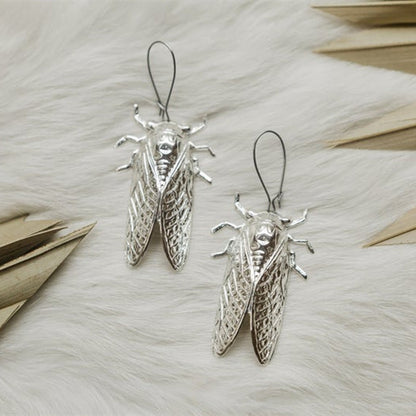 A person holding a pair of Maramalive™ Gothic Cicada Earrings.