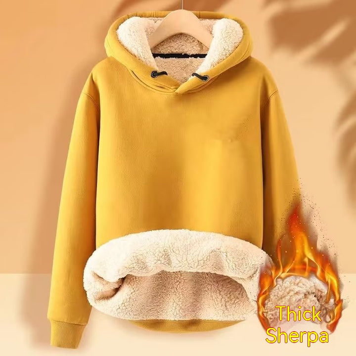 A Men's Fleece Hoodie Winter Lined Padded Warm Keeping Loose Hooded Sweater from Maramalive™ in mustard yellow with a thick sherpa wool lining and a hood with drawstrings is hanging on a wooden hanger. The lower part of the interior and the hood feature the cozy material. A "Thick Sherpa" graphic with a flame icon is overlayed on the bottom right.