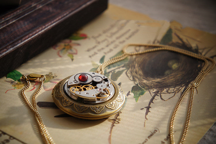 A close up of a Maramalive™ Gemstone Photo Box Steampunk Handmade Mechanical Movement Necklace on a table.