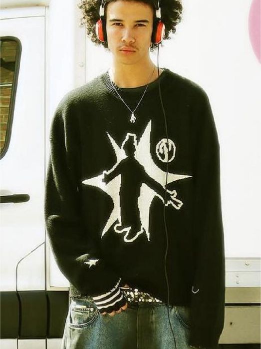 A person with curly hair stands in front of a white vehicle wearing large headphones, a black Hip-Hop Street Gothic Print Knitted Sweater by Maramalive™, and loose jeans that exude street fashion.