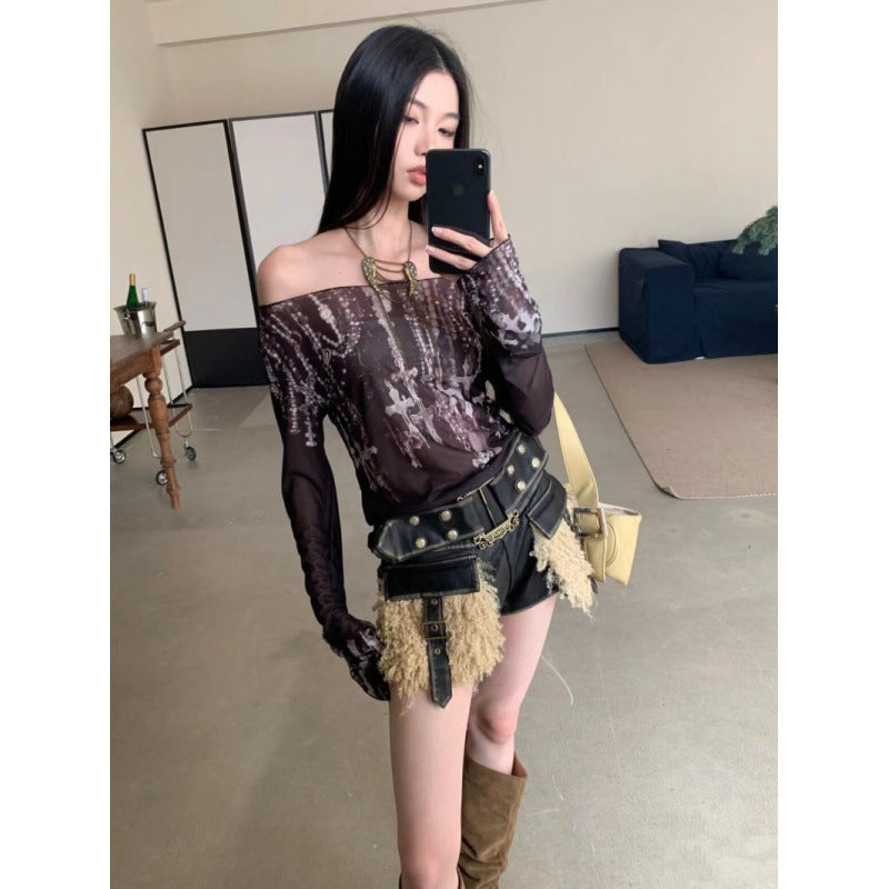 A woman takes a mirror selfie in a room, wearing an Off-shoulder Printed Mesh Long Sleeve Bottoming Shirt Sun Protection Shirt by Maramalive™, black shorts with tassels, and brown boots, embodying an effortless urban style.