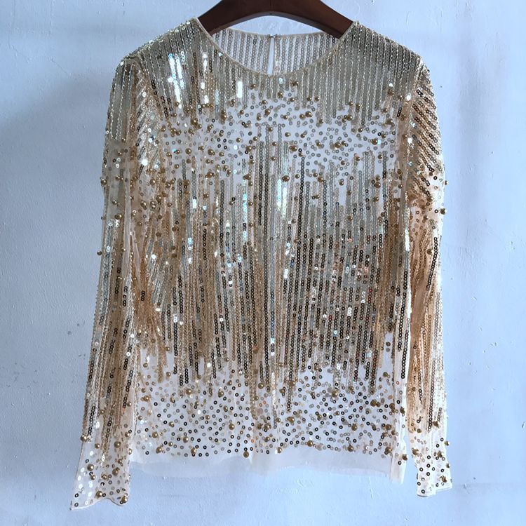 A long-sleeved women's top, crafted from polyester fiber, adorned with vertical gold sequins and beadwork, hanging on a hanger against a plain white background. This stunning sheer piece is free size for flexible styling. Introducing the Fashion Bottoming Shirt Sequined Top For Women by Maramalive™.