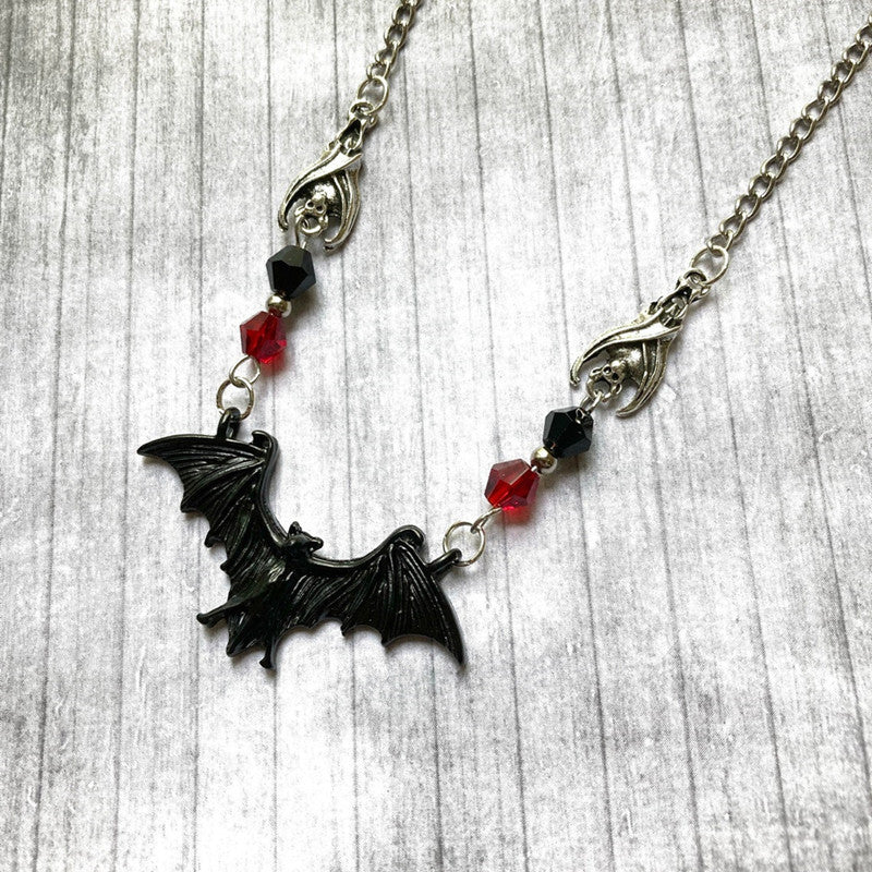 A black and red Bat Wing Necklace from Maramalive™ on a mannequin.