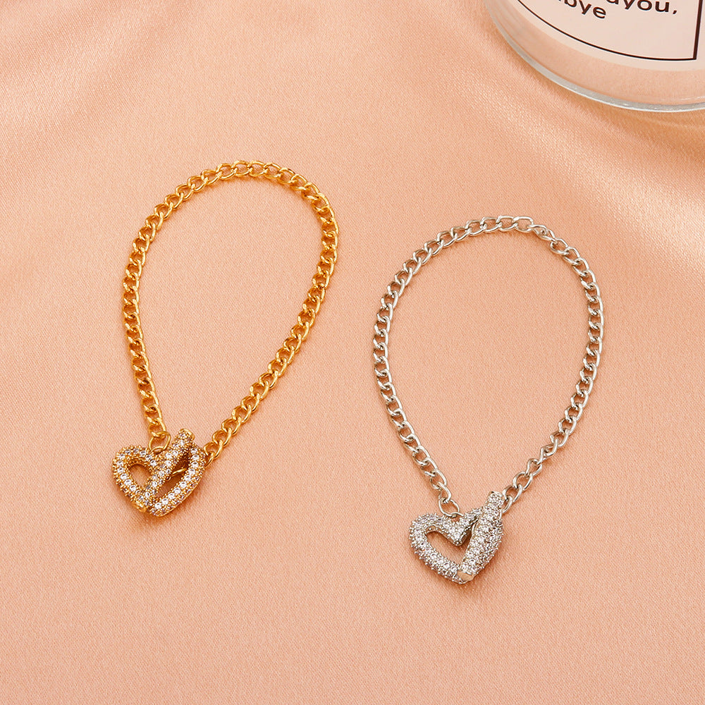 Two Cold Wind Love Heart Bracelets by Maramalive™ on a table next to a candle.