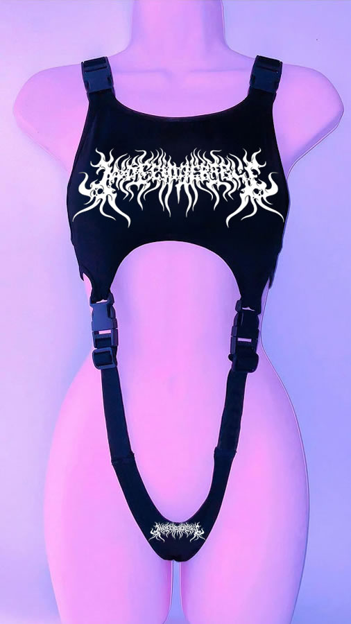 A black faux leather harness with white graphic text displayed on a mannequin against a purple background. This vintage inspired goth style piece features shoulder straps and one that goes from the chest to the lower torso, creating a striking '90s Throwback Y2K Gothic Style Cropped Vest for Goths by Maramalive™.