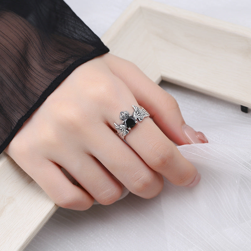 A Maramalive™ Striking Sterling Silver Crown and Wings Ring with a black stone.
