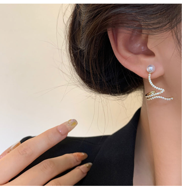 A woman wearing a pair of Maramalive™ Sterling Silver Needle Micro-inlaid Exquisite Snake-shaped Ear Clip Stud Earrings with a wavy design.