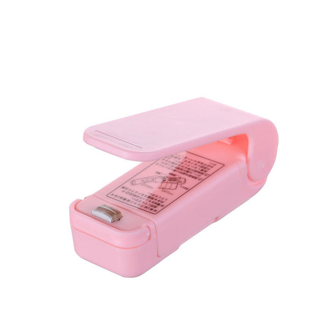 A pink and white Mini Sealing Machine charger sitting on top of a green surface, made by Maramalive™.