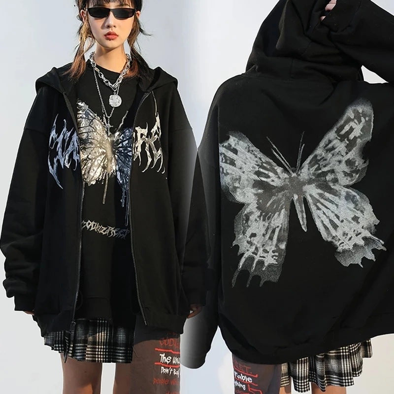 A person modeling a versatile black **Maramalive™ Comfy Zipper Hoodie for Fall: Hooded Sweatshirts & Sweaters** with a large, abstract butterfly design on the back. The front features graffiti-style text. The hoodie complements a plaid skirt and layered necklaces perfectly, making it an ideal autumn companion for those looking to blend style with comfort.