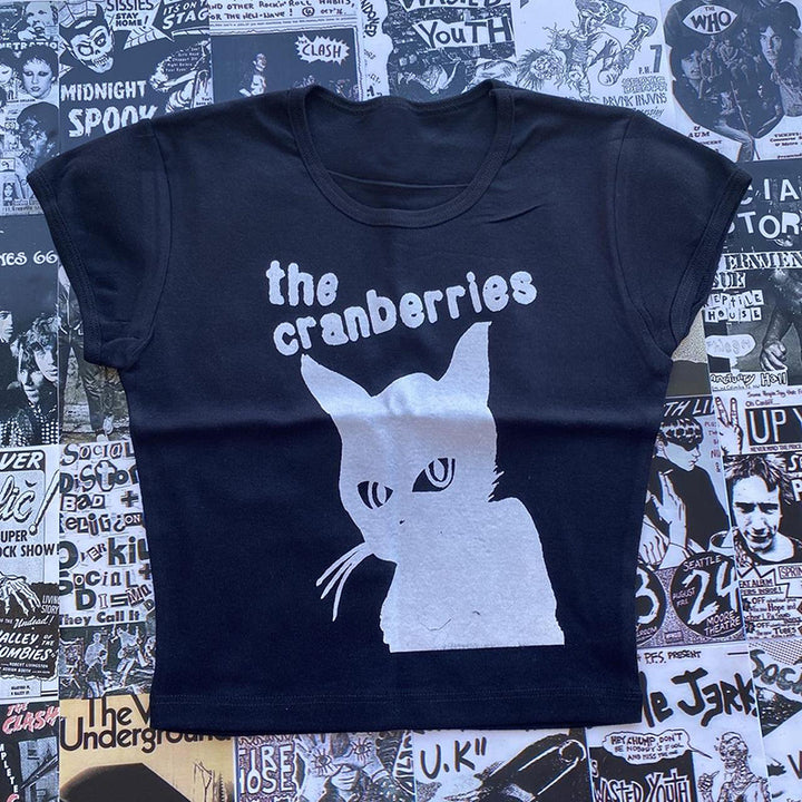 A slim fit black Maramalive™ Gothic Street T-shirt Women's Printed Black Top with "The Cranberries" and an image of a cat printed on the front, laid on a background of various black-and-white band posters.