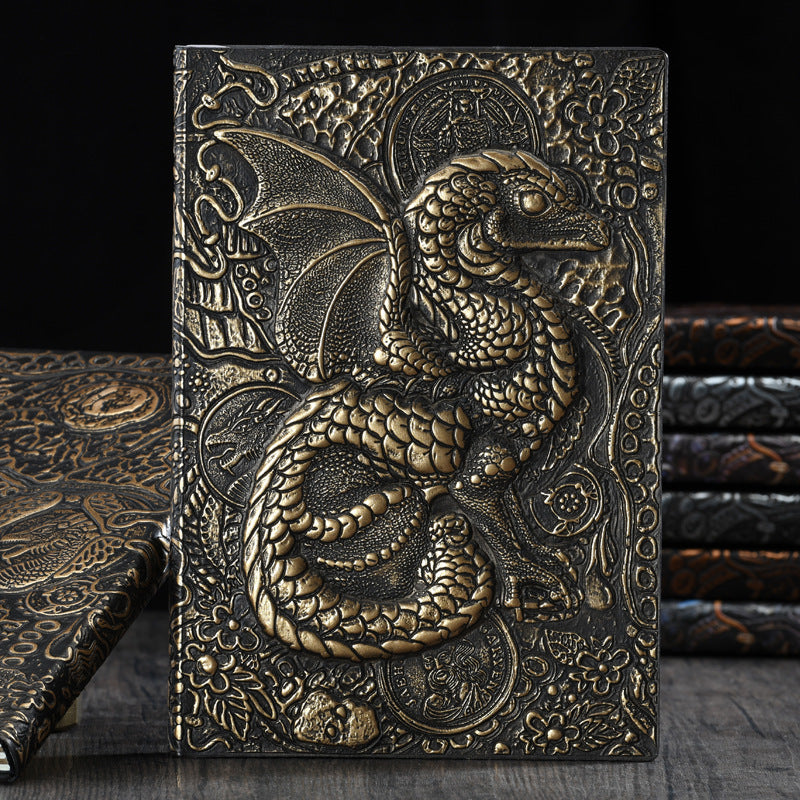 Three Maramalive™ Vintage Anaglyph Dragon Notebook Retro Planners in Bronze lined up next to each other on a table.