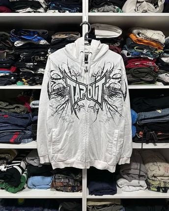 A white Men's Skeleton Zipper Hooded Sweatshirt with a black and white graphic design and the word "Maramalive™" hangs on a rack surrounded by folded clothes on shelves.