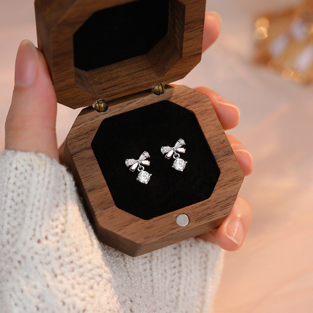 A woman wearing a white shirt and a pair of Maramalive™ Women's Graceful And Fashionable Pure Silver Zircon Bow Stud Earrings.