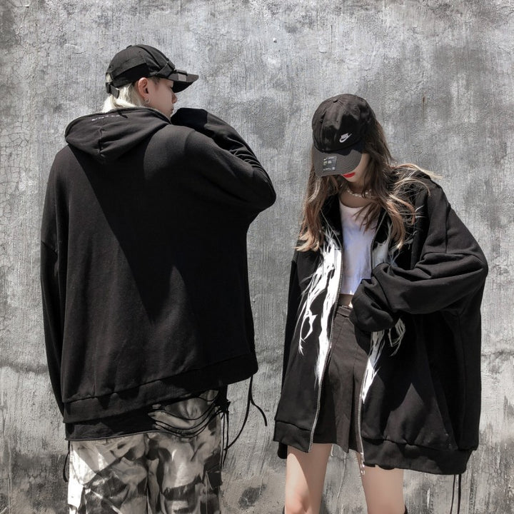 Two people in casual streetwear, both wearing black hats and oversized FallWinter College BF Wind Hooded Cardigan Sweatshirt National Tide Printed Loose Sports Casual Hoodies from Maramalive™, stand against a concrete wall. One is facing away, while the other looks down.