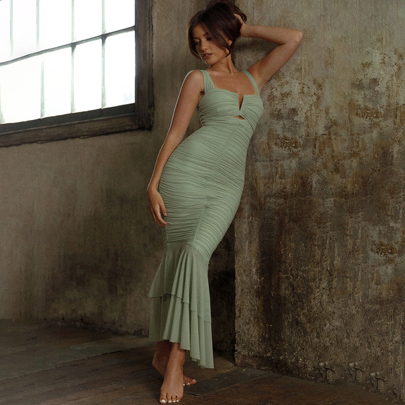 A woman in a green Women's Fashion Suspenders Stitching dress, by Maramalive™, leaning against a wall.