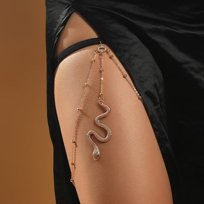 A woman is wearing a Maramalive™ Bohemian Boho Gold Color Metal Beaded Chain Thigh Chain For Women Big Snake Pendants Leg Chain Body Jewelry Beach Style Gift on her thigh.