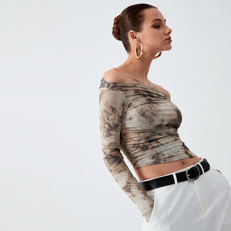 A person with tied-back hair, wearing a Maramalive™ Printed Off-neck Long Sleeve Backless Pleated Top and white khaki pants paired with a black belt featuring a circular buckle, poses against a plain background.