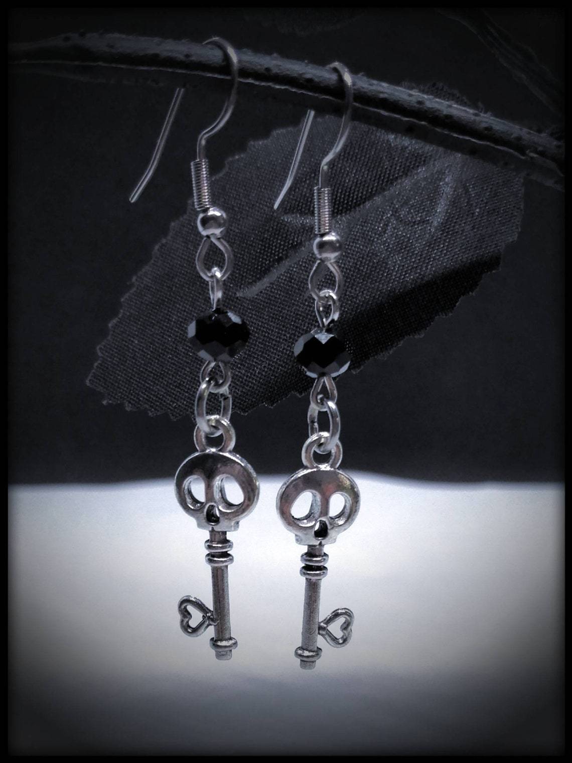 A pair of CJ Fashion Gothic Skull Earrings Jewelry Gift with a key on them.